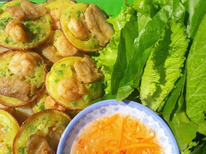 Bánh khọt vàng, rau xanh và bát nước chấm