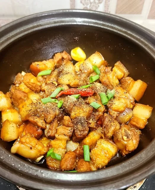Nồi thịt kho vàng nâu với hành lá và ớt